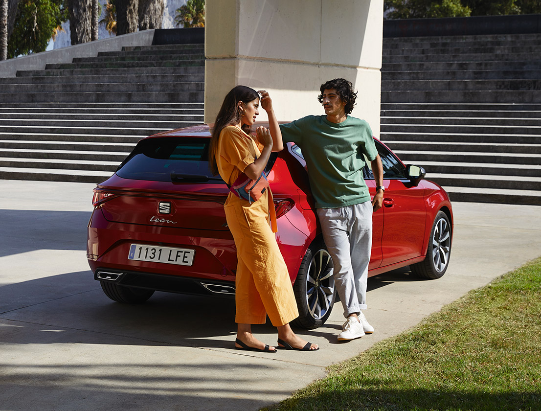 couple s'appuyant sur la nouvelle seat leon de couleur desire red 