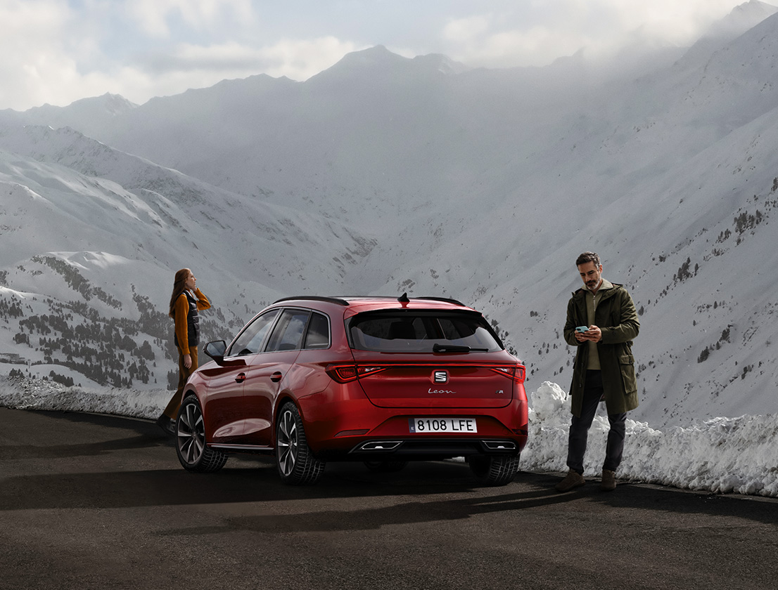 vue de l'arrière de la seat leon de couleur desire red avec un couple admirant la montagne