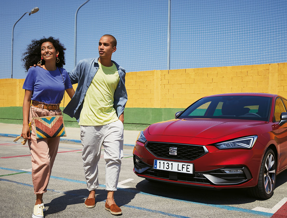 couple parlant à côté d'une seat leon de couleur desire red